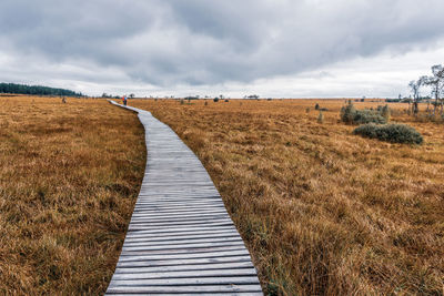 View of boardwalk on field against sky