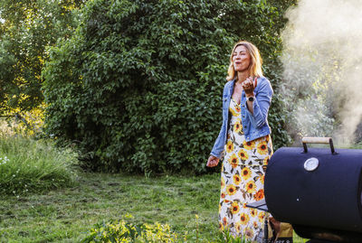 Woman standing near grill in garden