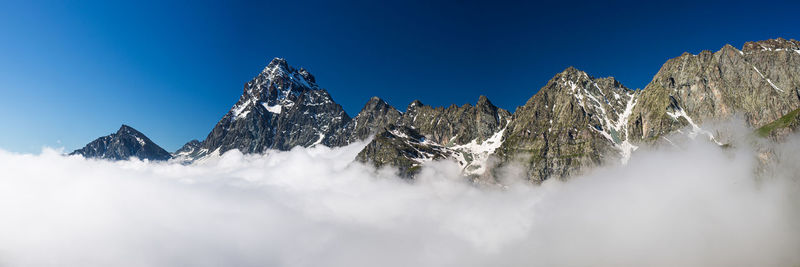 Low angle view of snowcapped mountains against blue sky