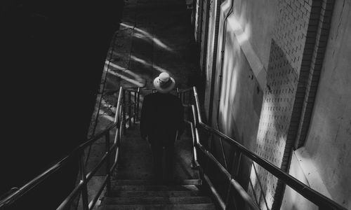 Rear view of man walking on staircase