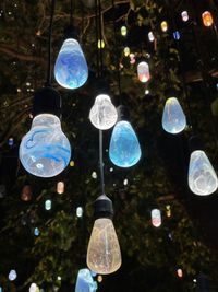 Low angle view of illuminated light bulbs hanging from ceiling