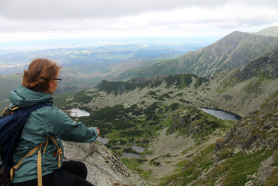 Rear view of man standing on mountain against sky