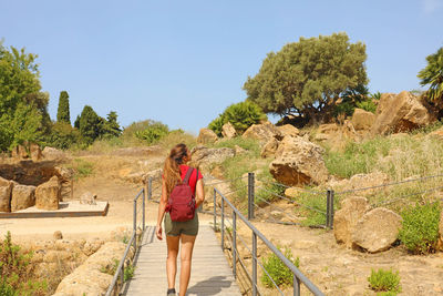 Rear view of woman walking on road against sky