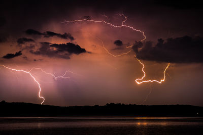 Lightning over calm lake at night