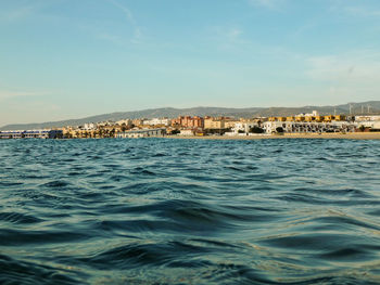 Scenic view of sea by townscape against sky