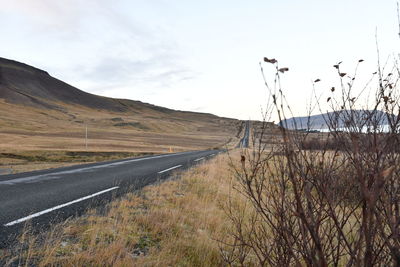 Road leading towards mountains against sky