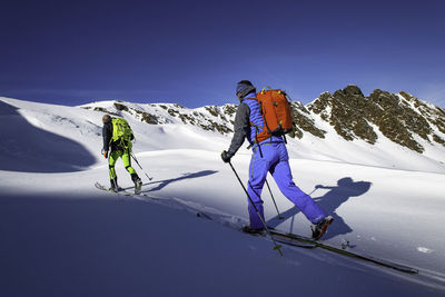 People skiing on snowcapped mountain against sky during winter