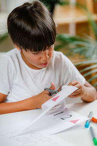 Child cutting cards with shapes in a preschool assessment test.