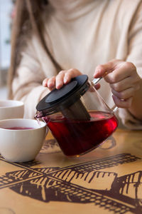 Midsection of woman holding coffee cup on table