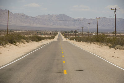 Road by mountains against sky