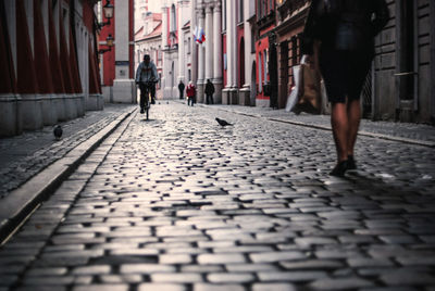 People on paving street amidst buildings