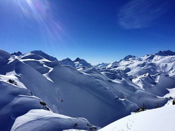 Scenic view of snowcapped mountains against blue sky