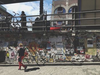 Full length of woman standing against graffiti in city