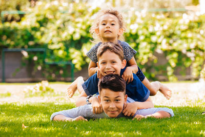 Portrait of happy siblings playing at backyard