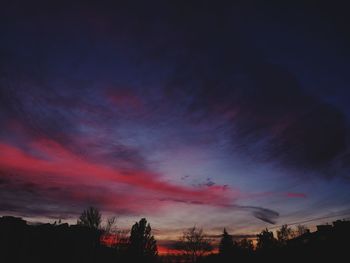 Low angle view of silhouette trees against dramatic sky