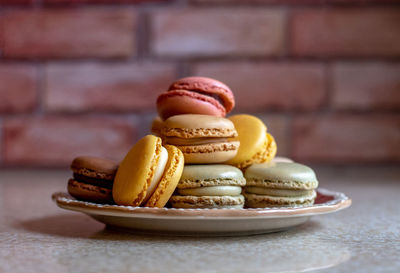 Plate of french macarons in front of a brick wall in the kitchen