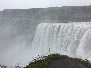 Scenic view of waterfall against sky