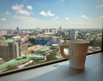 Close-up of coffee served on table against buildings in city