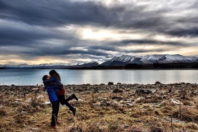 Scenic view of lake and mountains against cloudy sky