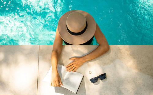 Young woman reading a book in the pool