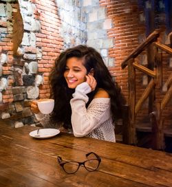 Portrait of a smiling young woman sitting on table