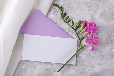 Invitation card mockup in veri pery envelope with freesia flower.