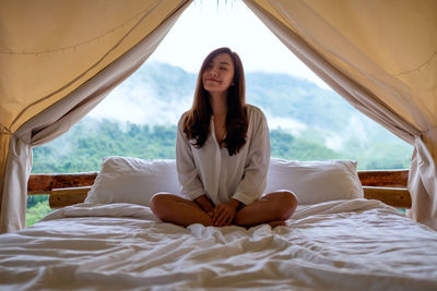 Portrait of smiling woman sitting on bed