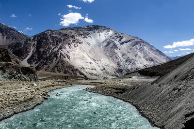 River flowing by mountain against sky