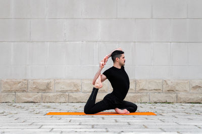 Full length of man exercising against wall