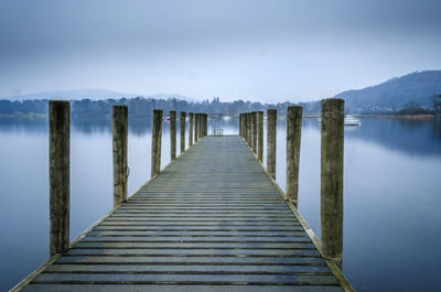 Wooden pier over lake against sky