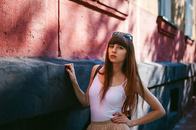 Portrait of young woman standing by building