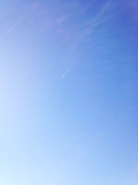 Low angle view of vapor trails in blue sky