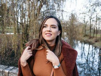 Portrait of happy young woman in winter clothes in park.