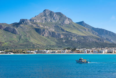 Scenic view of sea and mountains against clear blue sky