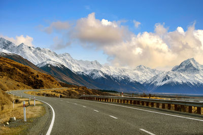 Road leading towards snowcapped mountains against sky