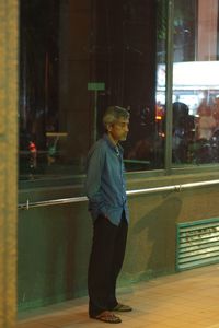 Side view of man standing by window