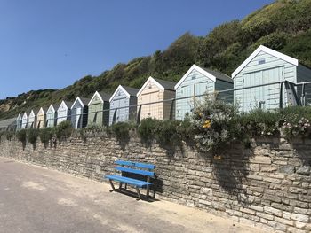 View of benches by building against clear blue sky