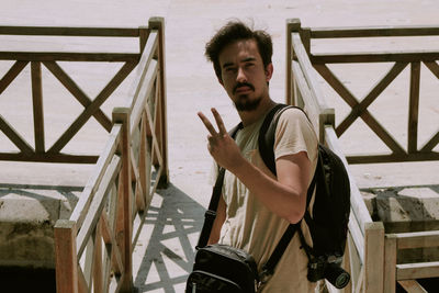 Portrait of young man standing against railing