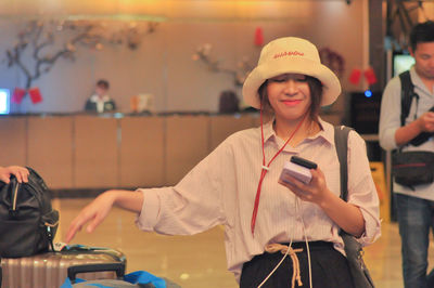 Portrait of smiling young woman using smart phone at airport