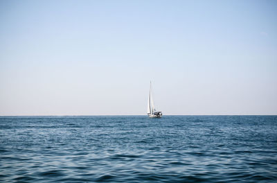 Sailboat sailing on sea against clear sky