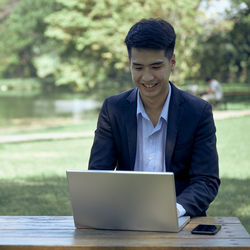 Young man using mobile phone while sitting on table