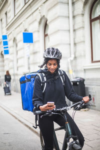 Food delivery woman using smart phone on street in city