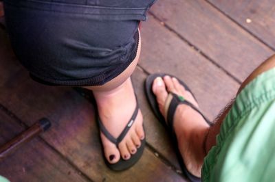 Low section of people wearing slippers on boardwalk