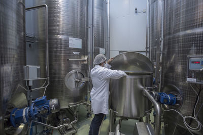 Lab technician in pharmaceutical plant in front of tanks