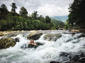 Scenic view of waterfall in forest against sky