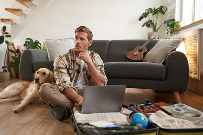 Young woman using laptop while sitting on sofa at home