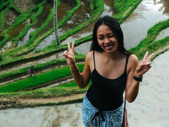 Beautiful young woman standing against rice paddy 