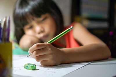 Close-up of girl writing on paper at home