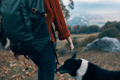 Midsection of woman with dog standing at home