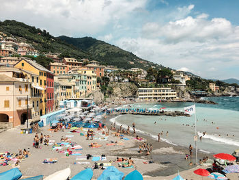 People on beach by buildings against sky in city